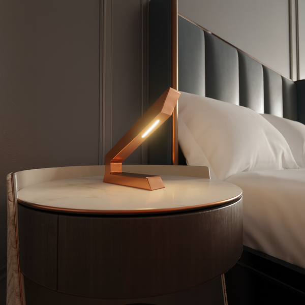 Copper finish handcrafted oak angular wooden lamp by WOOM, illuminating a marble bedside table next to a bed.