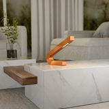 Curved copper finish LED lamp by WOOM, resting on a white marble table in a modern living room.