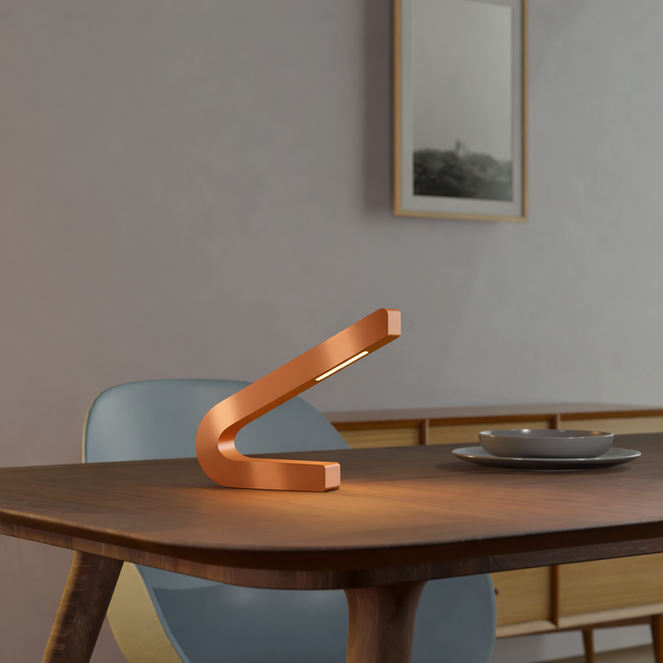 Curved LED lamp with a copper finish by WOOM on a wooden dining table, casting a soft light.