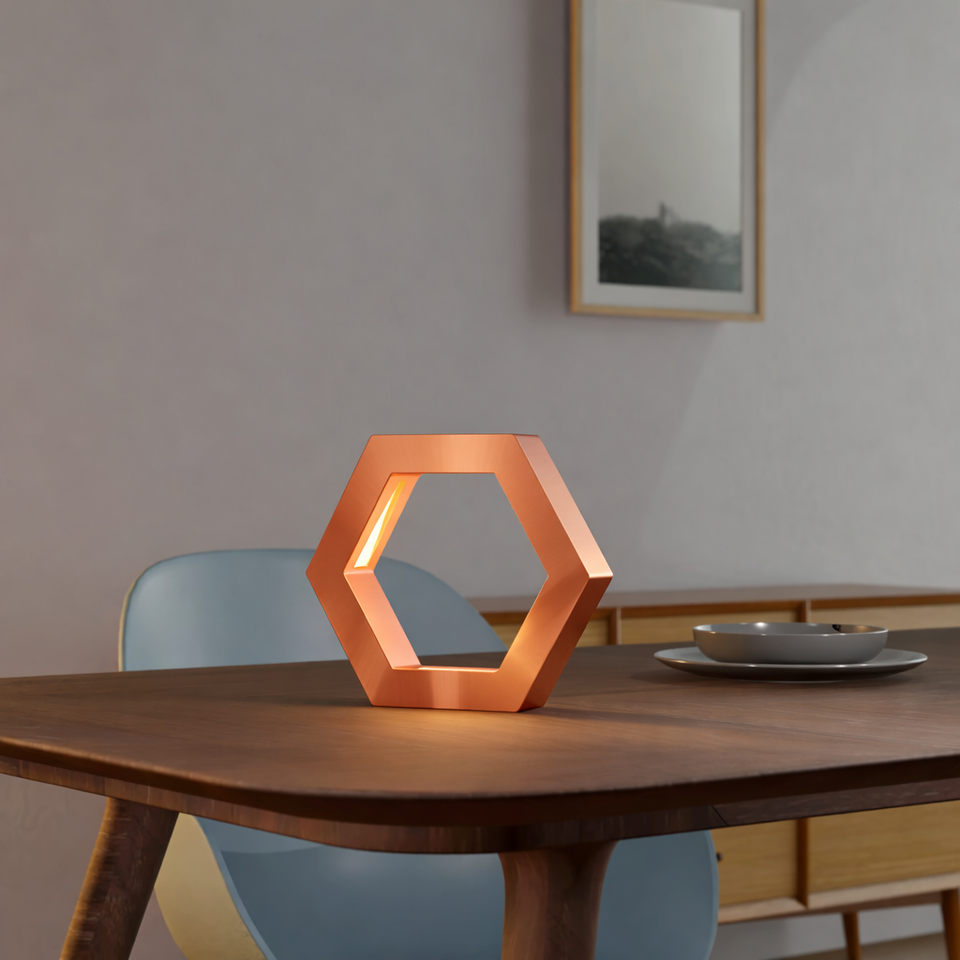 Copper finish hexagon lamp by WOOM, glowing warmly on a wooden dining table.