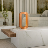 Copper finish wooden table lamp by WOOM, glowing orange, on a white marble table.