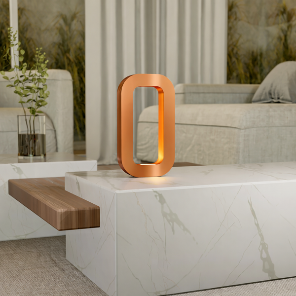 Copper finish wooden table lamp by WOOM, glowing orange, on a white marble table.