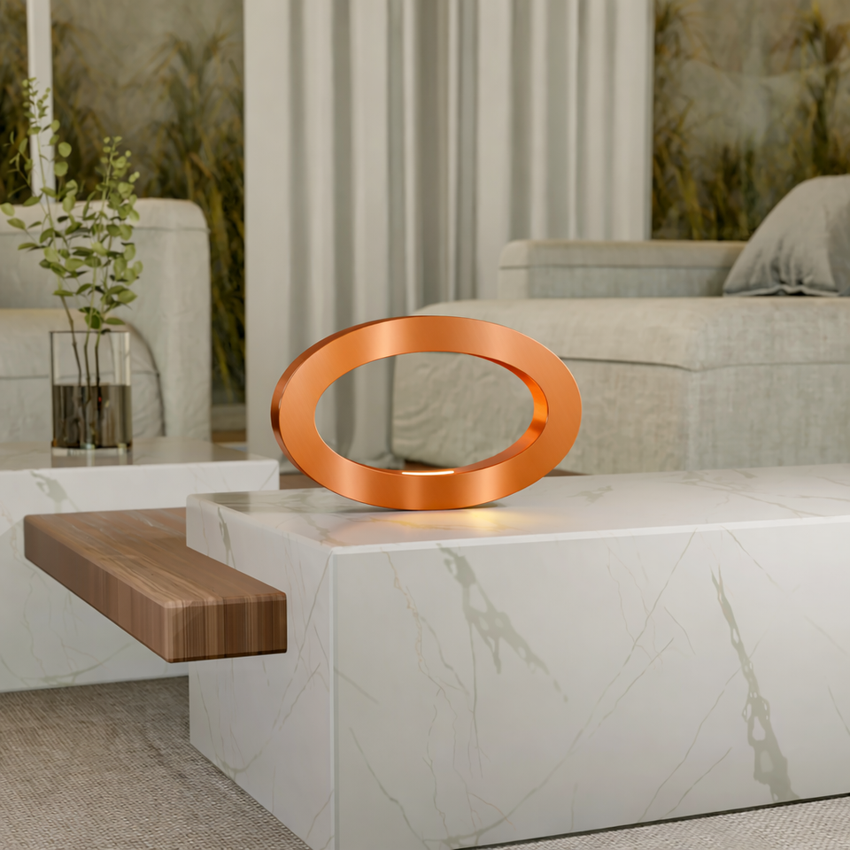 Copper finish oval lamp by WOOM, emitting warm light on a white marble coffee table.