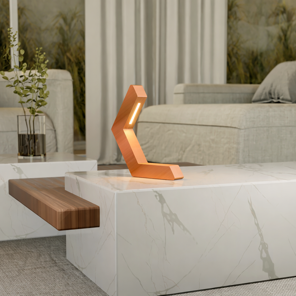 Copper finish geometric LED lamp of oak wood by WOOM, sitting on a white marble coffee table in a modern living room.
