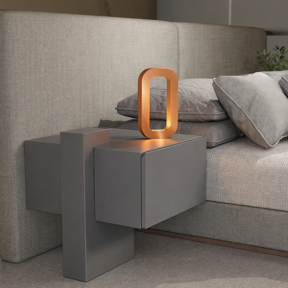 Copper finish rectangular table lamp by WOOM, glowing warm light on a modern grey nightstand.