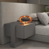 Copper finish oval table lamp by WOOM, illuminating a dark grey bedside table next to a textured grey bed.