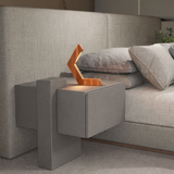 Copper finish geometric LED table lamp by WOOM, with a V-shaped design, sits on a grey nightstand.