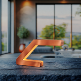 Copper finish Z-shaped lamp by WOOM with a warm glow, resting on a dark textured table against a bright window view.