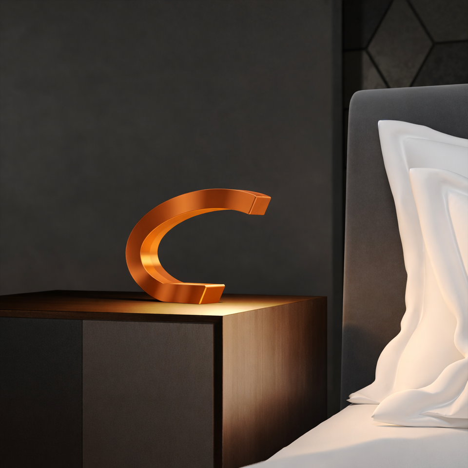 Copper finish oak C-shaped curved wood lamp by WOOM, casting a warm glow on a bedside table.