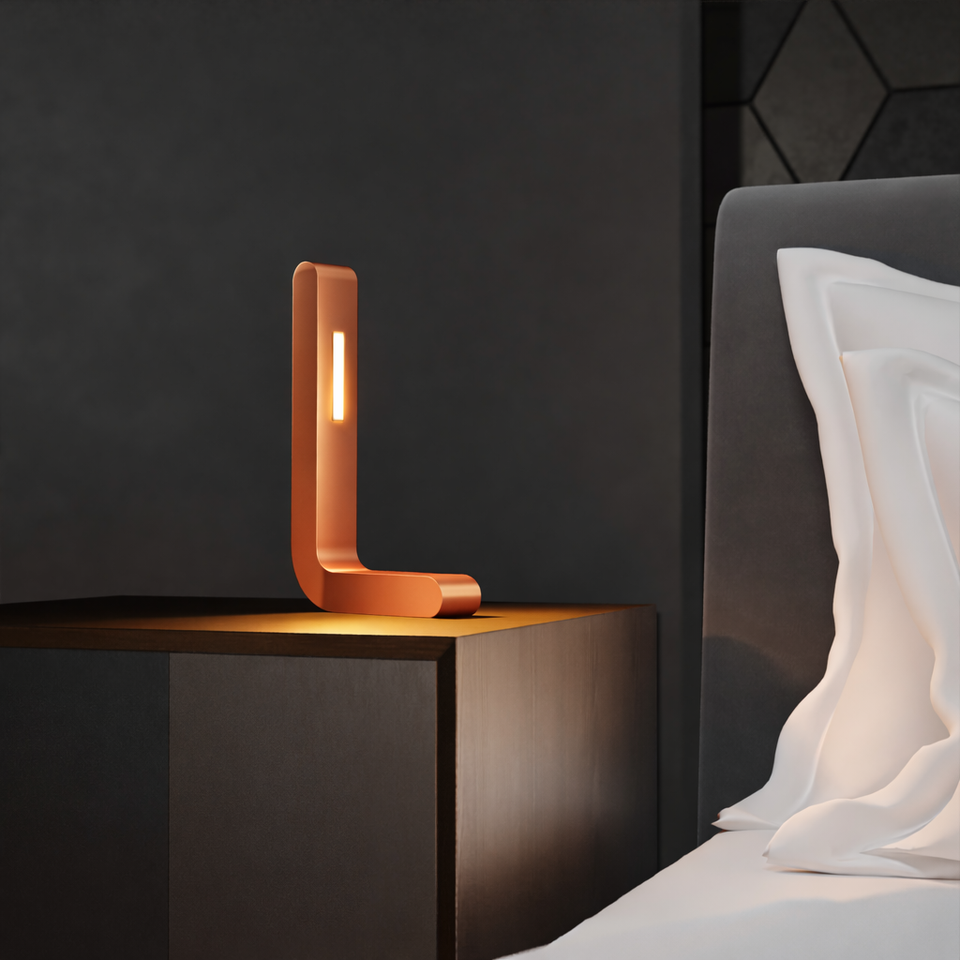 Copper finish L-shaped wooden LED lamp by WOOM on a dark nightstand, casting a warm glow in a minimalist bedroom with white bedding.