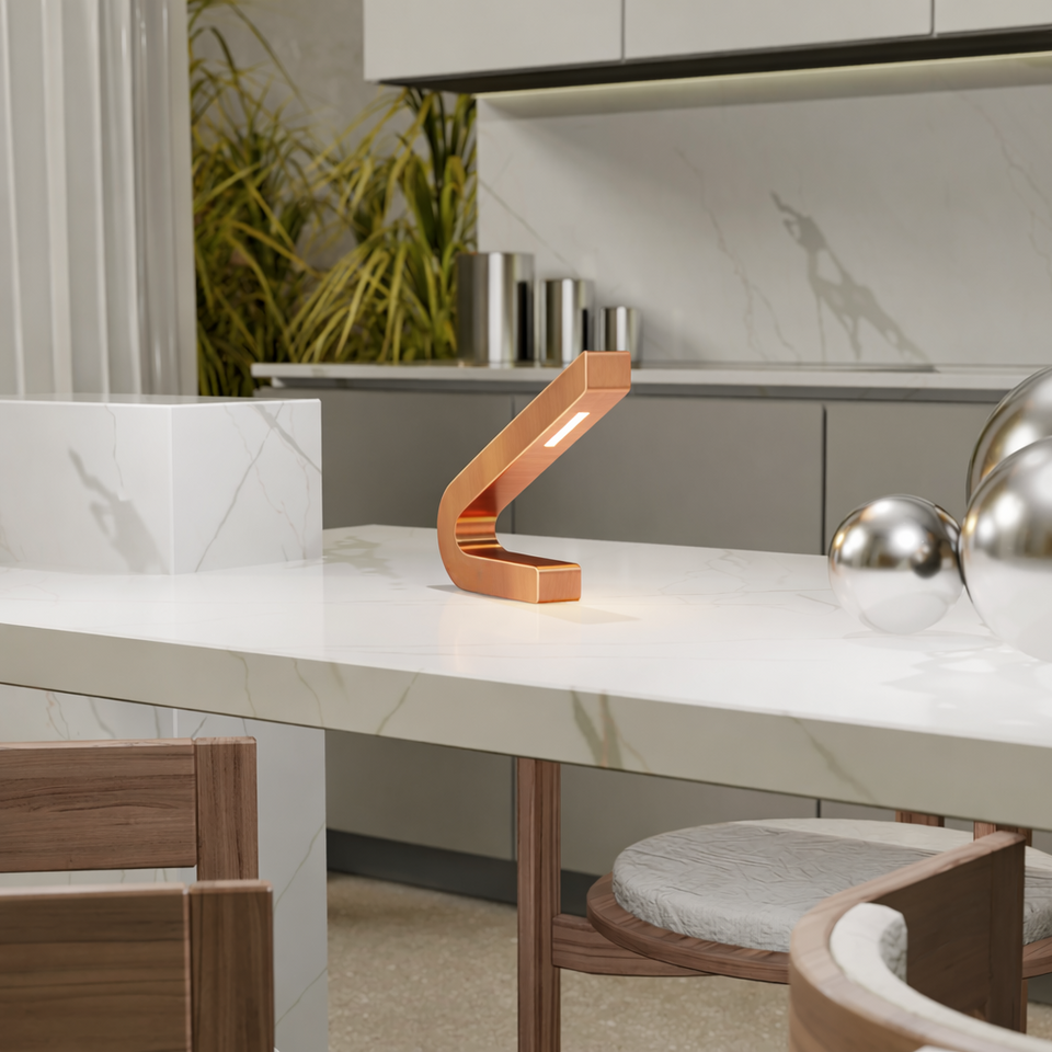 Copper finish curved LED lamp by WOOM, emitting a warm glow, positioned on a white marble counter.