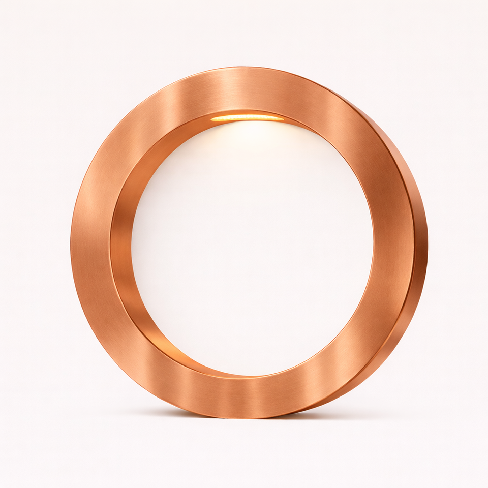 Copper finish round table lamp by WOOM, with warm light glowing from its brushed metallic frame onto a white interior.