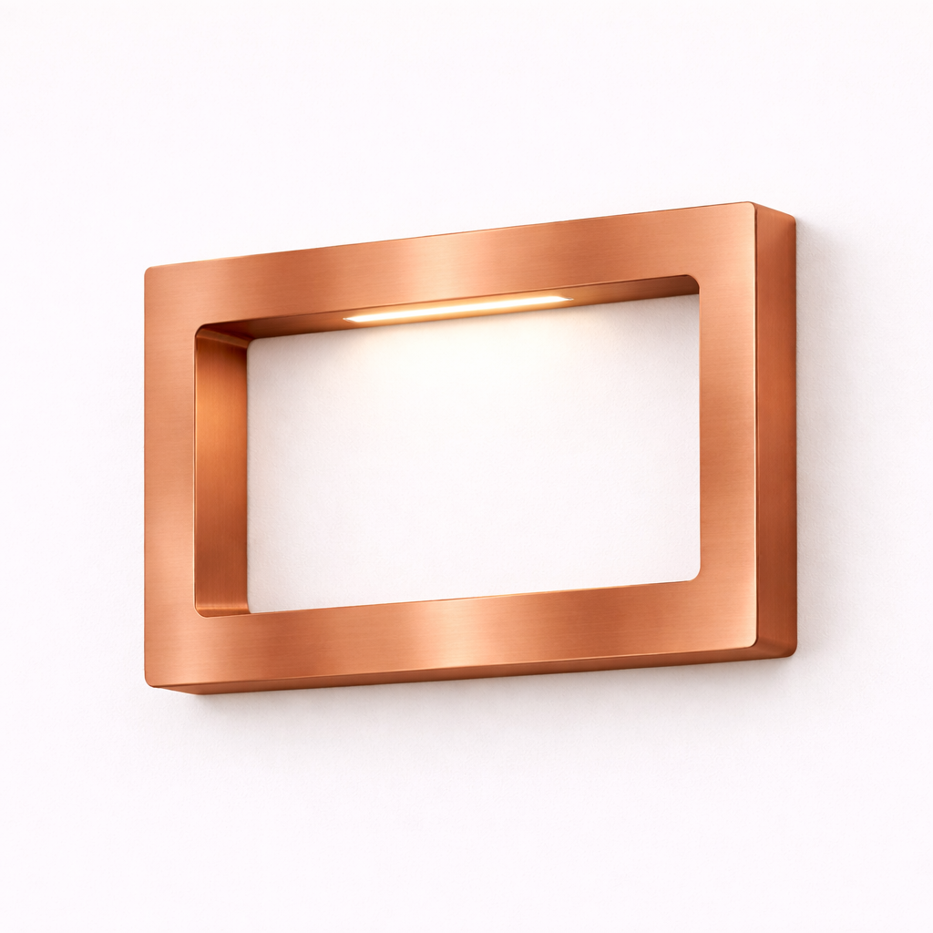 Rectangular copper finish LED lamp by WOOM, mounted on a white wall, emitting a warm light.