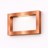 Rectangular copper finish LED lamp by WOOM, mounted on a white wall, emitting a warm light.