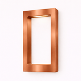 Rectangular wooden lamp with a brushed copper finish by WOOM, mounted on a white wall with a warm light glowing from its top interior.