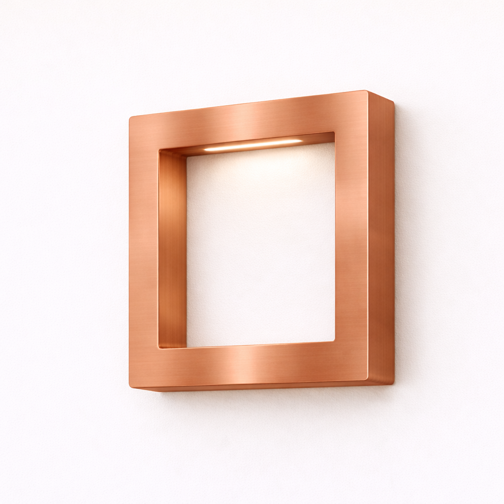 Brushed copper square lamp by WOOM with an integrated LED light, mounted on a white wall.