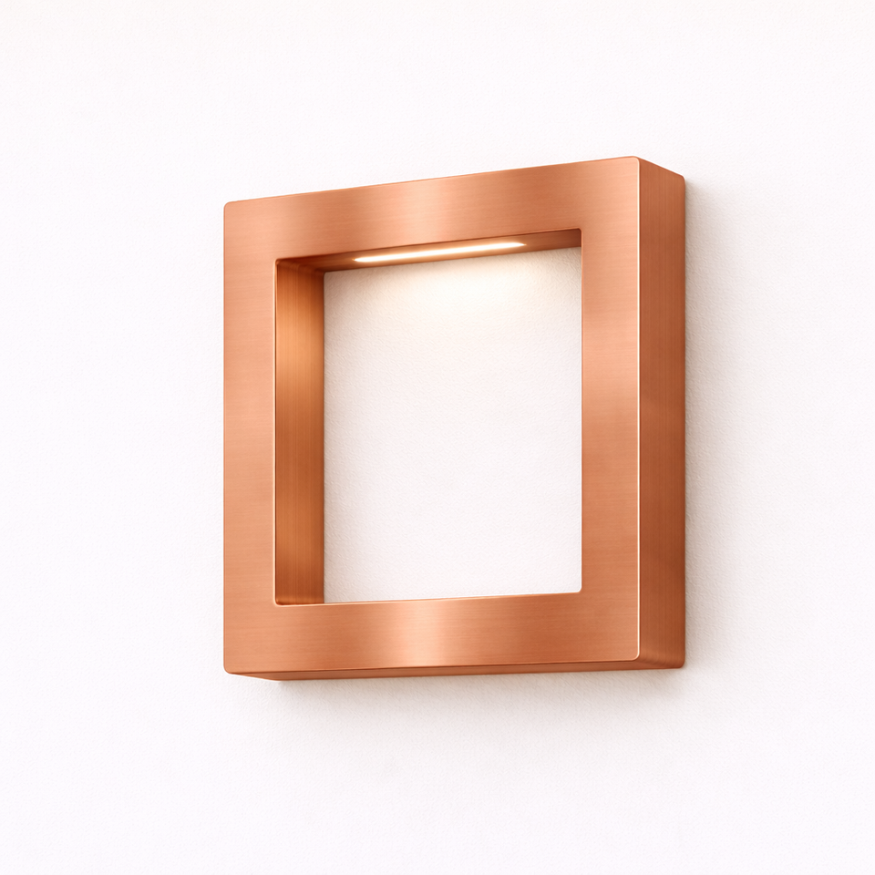 Brushed copper square lamp by WOOM with an integrated LED light, mounted on a white wall.