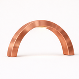 Copper-finished wooden arc table lamp by WOOM with an integrated light shining downwards.