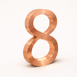 Copper finish oak infinity-shaped lamp by WOOM, with a soft glowing light and brushed metallic texture.