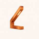 Copper finish modern LED lamp by WOOM, with a geometric L-shaped design and an illuminated strip.