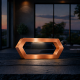 Copper finish hexagon LED lamp by WOOM emitting a warm glow, displayed on a dark stone surface.