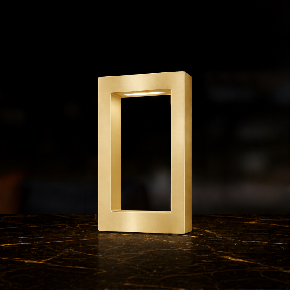 Gold finish rectangular wooden table lamp by WOOM with an internal light strip, standing on a dark marble surface.