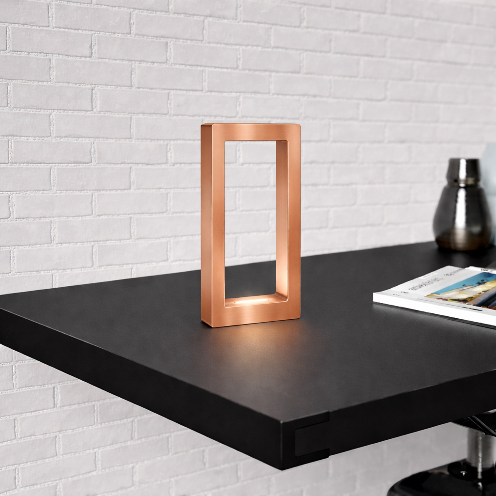 A rectangular copper finish oak table lamp by WOOM, with a warm glow on a black shelf.