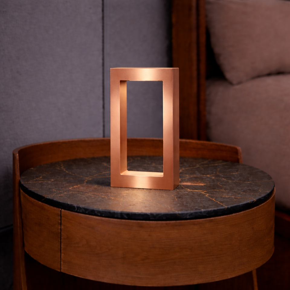 Rectangular oak lamp with a copper finish by WOOM, on a dark veined marble-top round wooden side table.