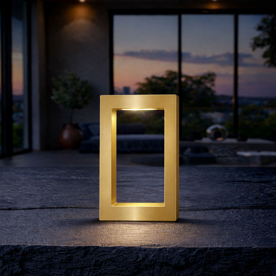 Rectangular wooden lamp with a gold finish by WOOM, emitting light on a dark stone surface.