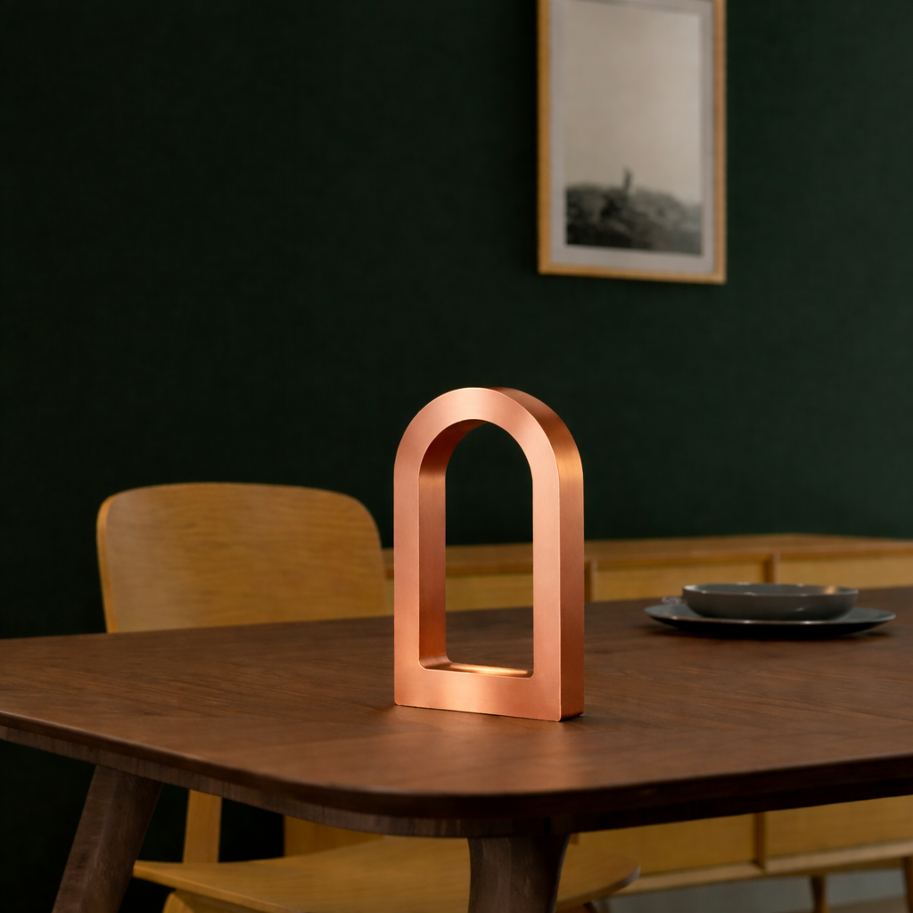 Copper Finish U-Shape Curved Desk Lamp by WOOM on a dark wood table with a dark green wall background.