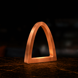 Copper finish arch desk lamp by WOOM with a brushed texture on a dark marble table.